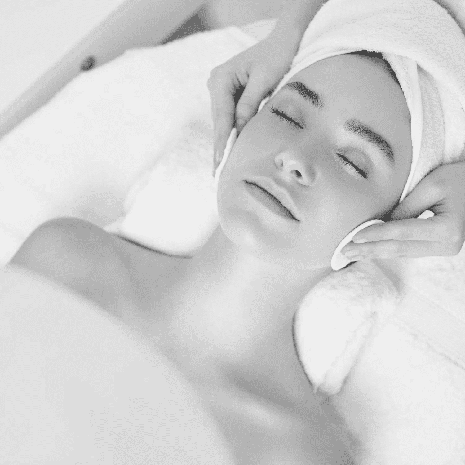 Facial treatment in progress at a spa; person relaxing with a towel wrapped around head.