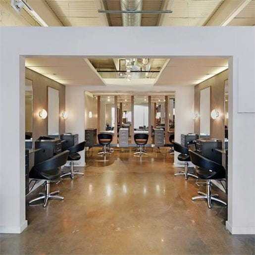Modern hair salon with stylish chairs and mirrors against a sleek, industrial backdrop.